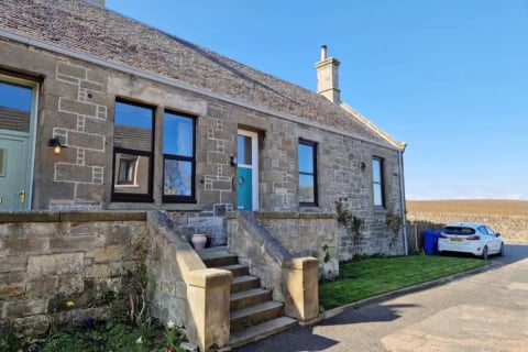 Linton - stone cottage with steps up to the teal front door